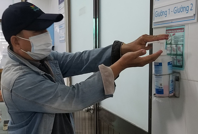 Thân nhân vệ sinh tay với cồn sát khuẩn nhanh tại hành lanh Bệnh viện Nguyễn Tri Phương. Ảnh: Lê Phương.